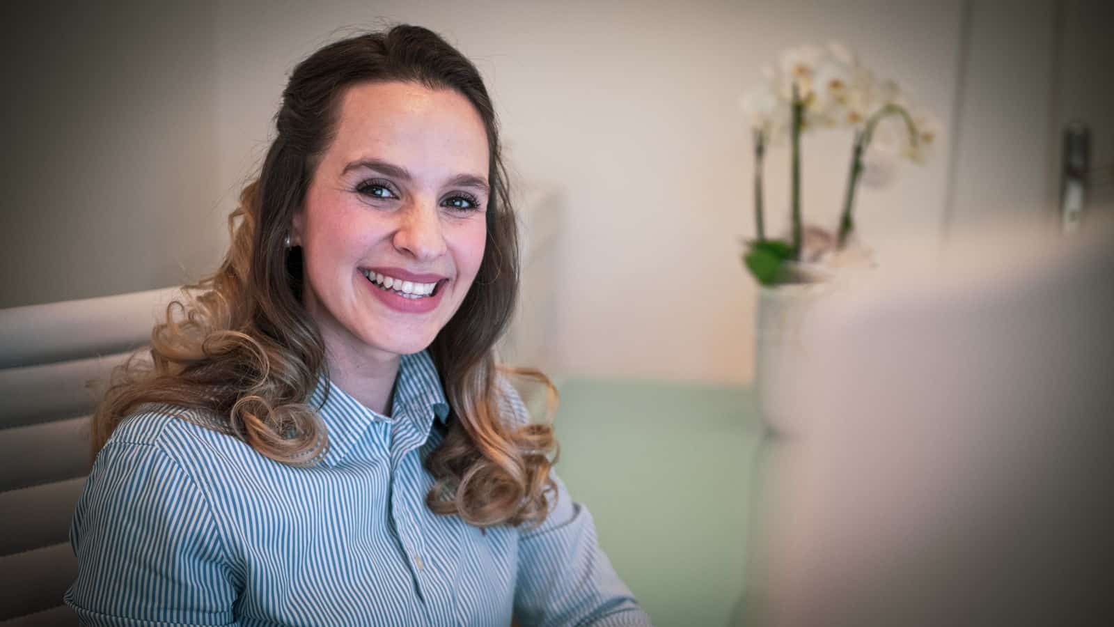Eine junge Dame sitzend am Empfang der Dental Praxisklinik